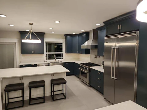 Finished kitchen with deep navy cabinetry, white countertops and stainless steel appliances