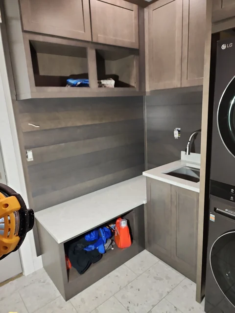 Utility and laundry room cabinetry with countertop, sink, wall storage and bench area