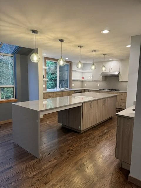 Finished contemporary kitchen cabinetry with a large island, waterfall countertop and pendant lighting